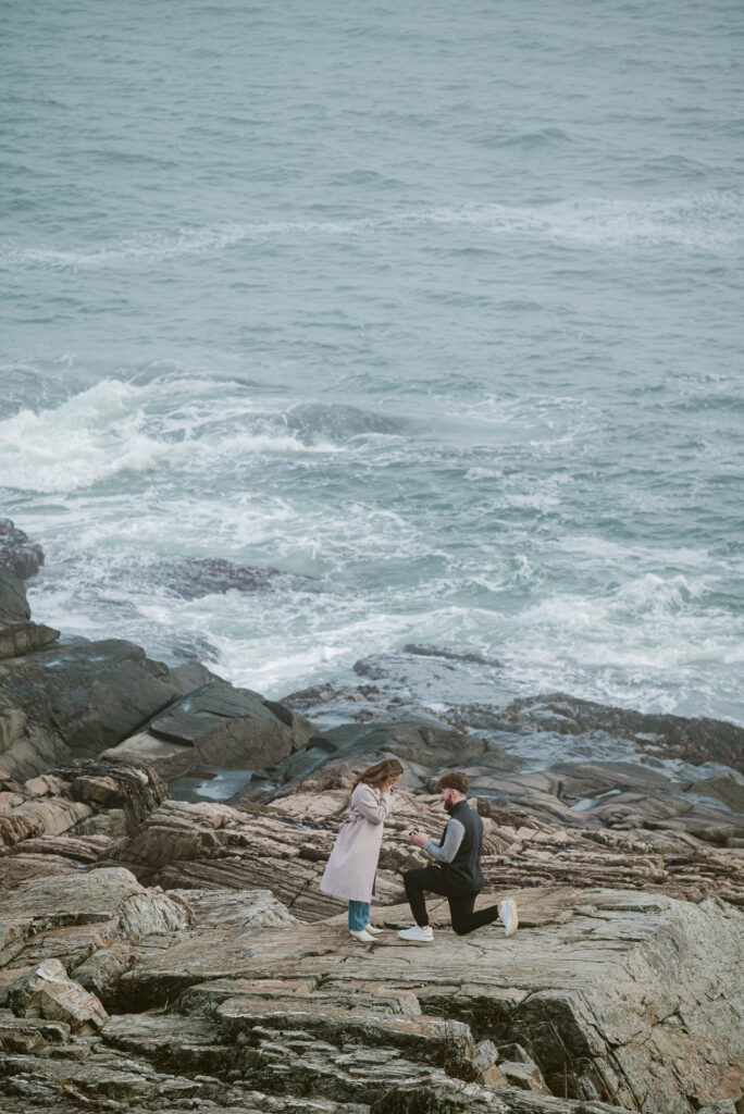 Man proposing to girlfriend on rocks at Cliff house Maine