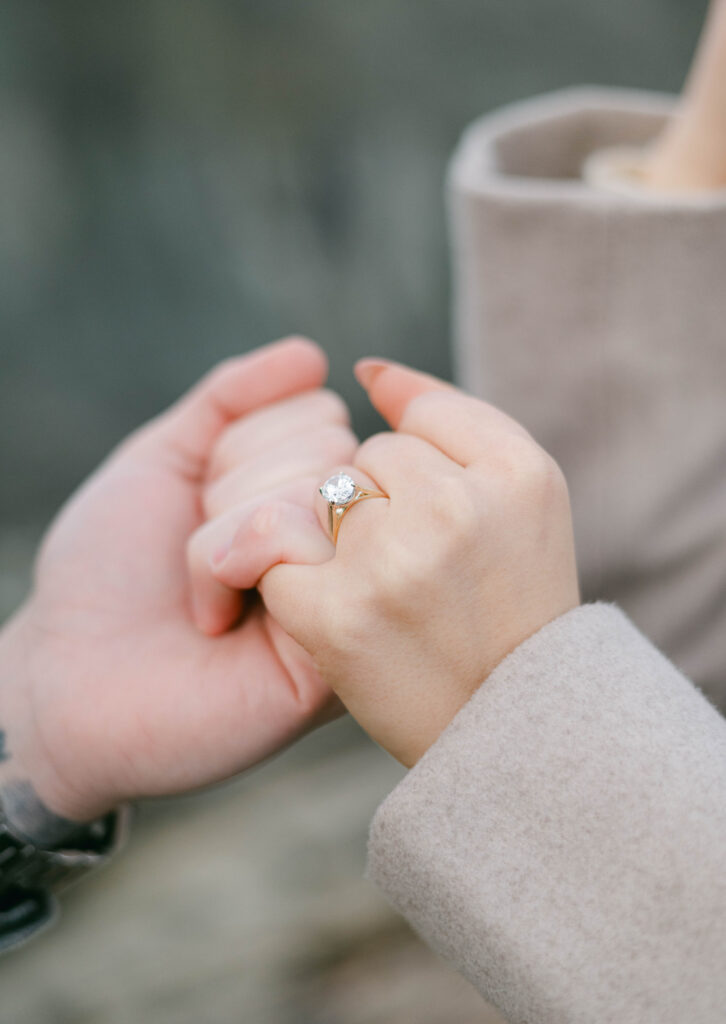 Engaged Couple with pinkies crossed and ring in view