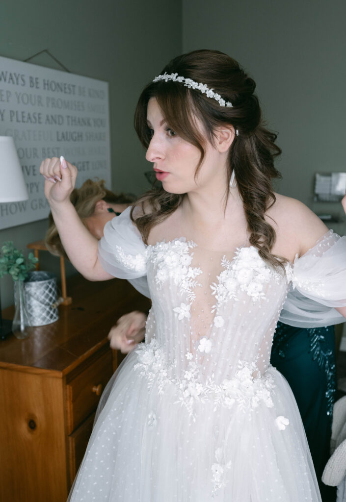 bride's mom zipping up her wedding dress