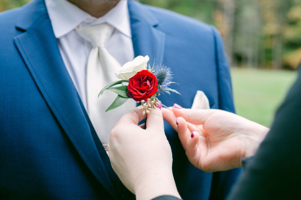 groom getting flowers put on his suit jacket