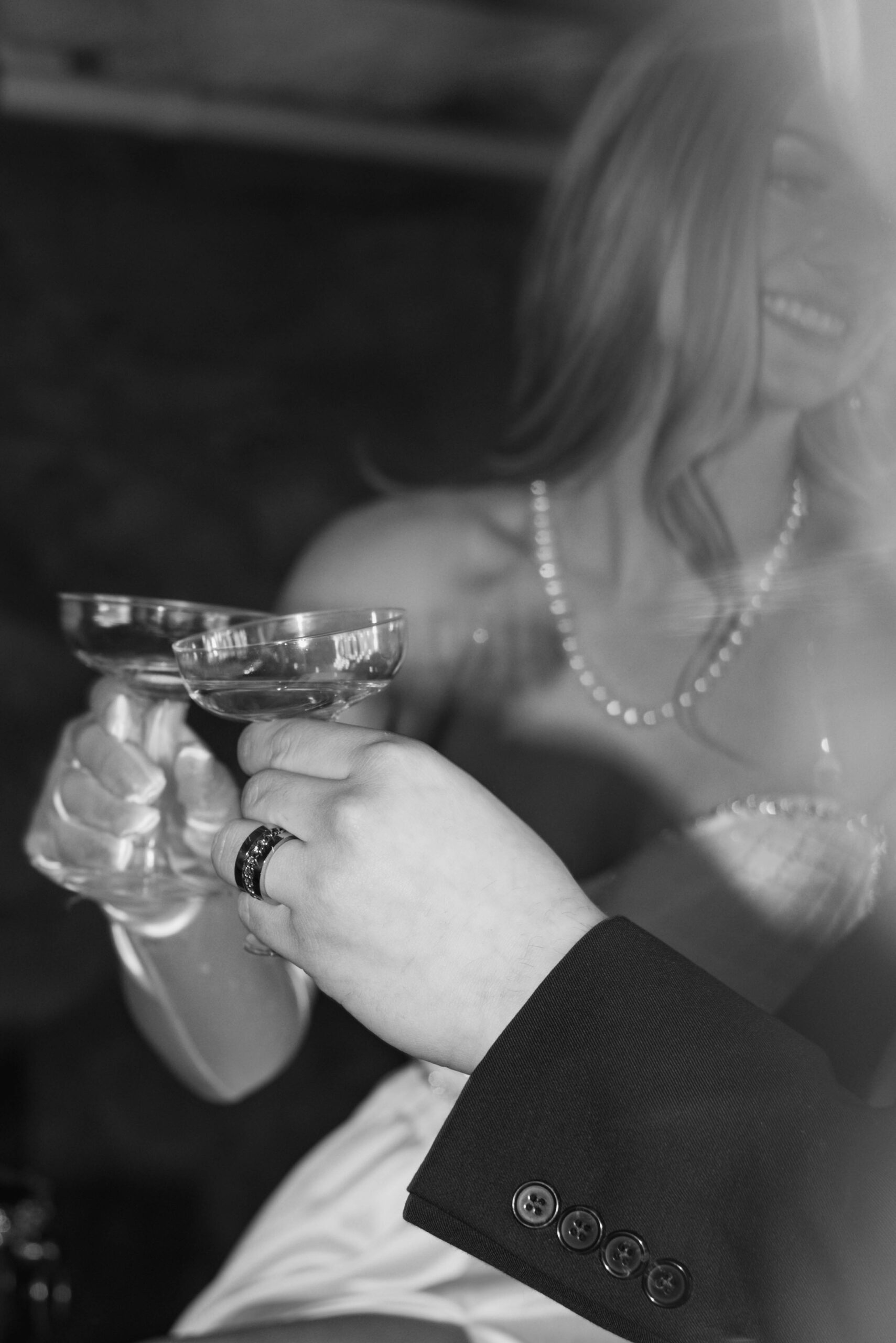 Black and white photo of bride and groom clicking glasses